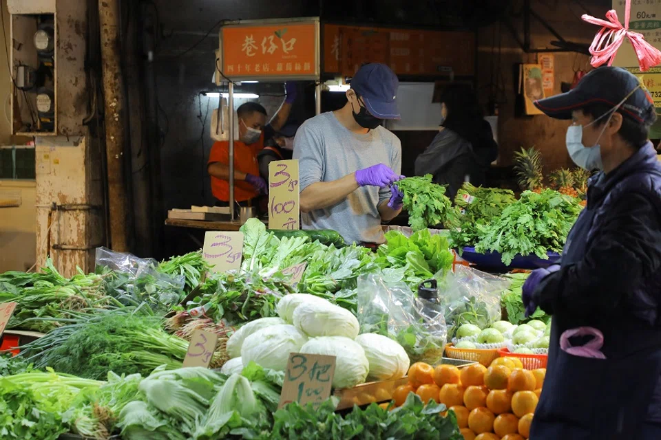 A man wearing a face mask to prevent the spread of Covid-19 works at a stall in a market in Taipei, Taiwan, 26 November 2021. (Annabelle Chih/Reuters)