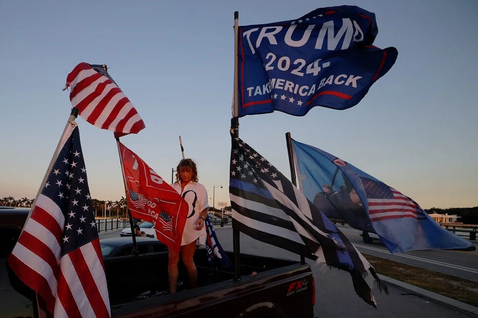 A woman flies flags from the bed of her pick-up truck outside US President-elect Donald Trump’s residence at Mar-a-Lago in Palm Beach, Florida, US, on 11 November 2024. (Brian Snyder/Reuters)