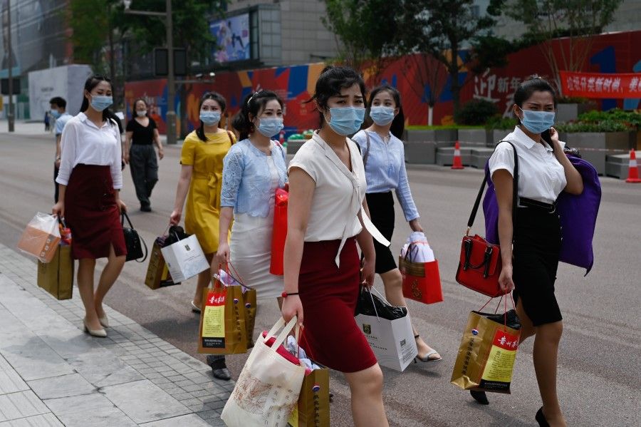 A group of women wearing face masks walk along a business street after shopping in Beijing on 23 June 2020. (Wang Zhao/AFP)