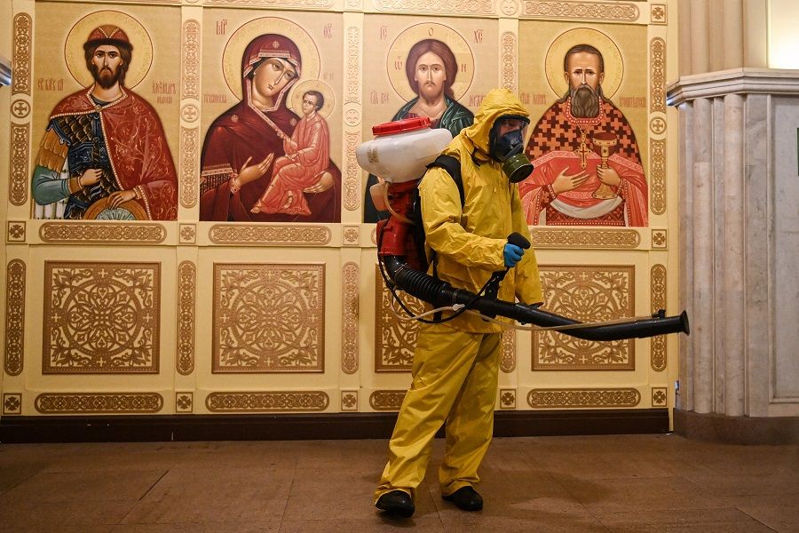 A serviceman of Russia's Emergencies Ministry wearing protective gear disinfects an Orthodox chapel at Moscow's Leningradsky railway station on 19 October 2021. (Kirill Kudryavtsev/AFP)