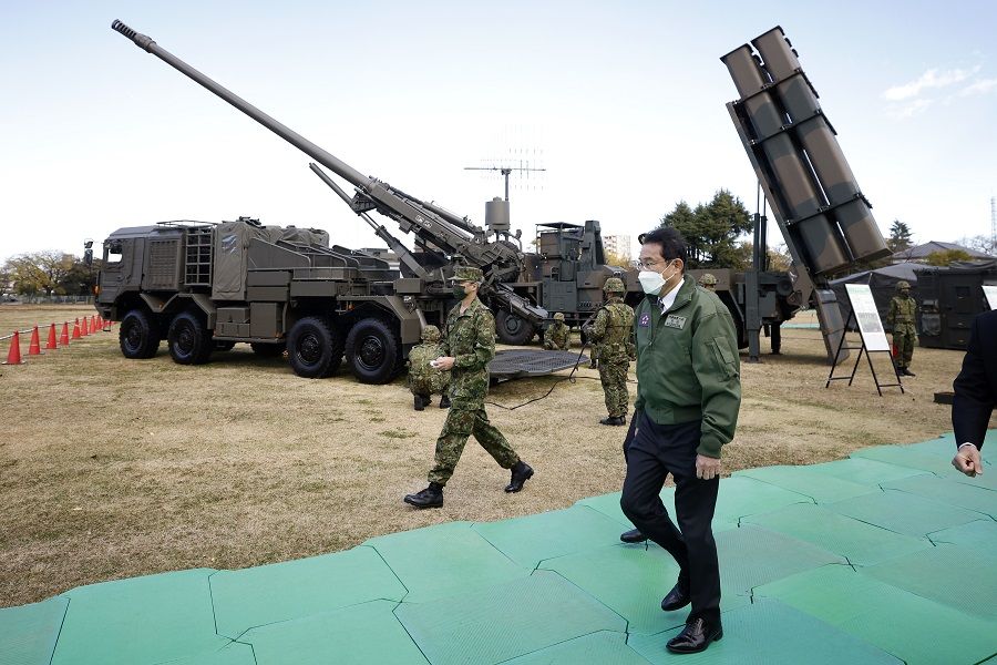 Japanese Prime Minister Fumio Kishida walks past a Japan Ground Self-Defense Force (JGSDF) Type 19 155 mm wheeled self-propelled howitzer, rear left, and a Type 12 surface-to-ship missile, rear right, as he inspects equipment during a review at JGSDF Camp Asaka in Tokyo, Japan, on 27 November 2021. (Kiyoshi Ota/Bloomberg)