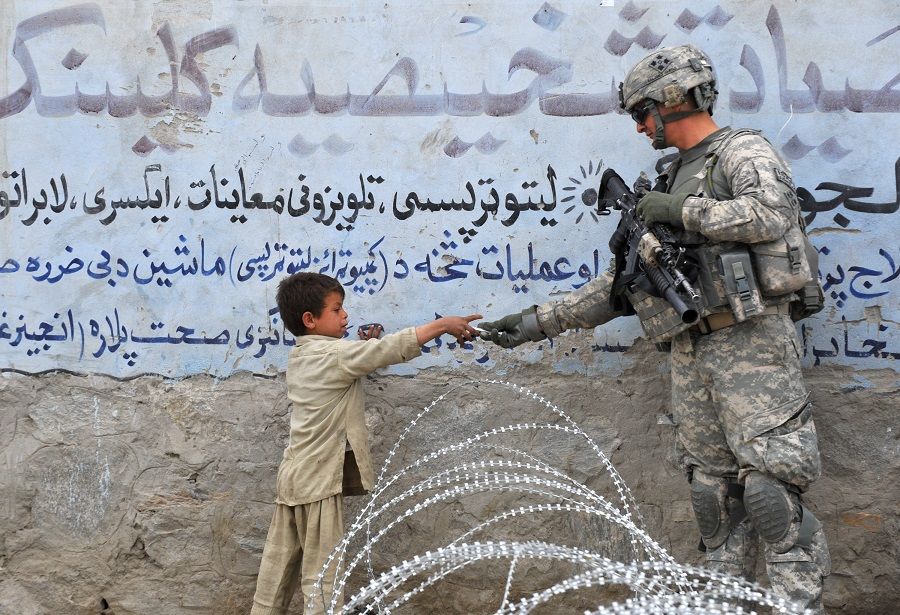 In this file photo taken on 20 February 2010, a US soldier from 4th Infantry Division 4 Brigade Alpha Company presents a gift to an Afghan child during a patrol at Khogiani in Nangarhar, Afghanistan. (Kim Jae-hwan/AFP)