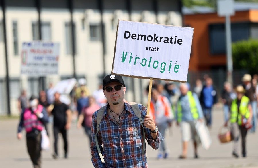 A man holds up a sign reading "democracy instead of virology" as he attends a protest against the government's restrictions following the coronavirus disease (COVID-19) outbreak, at Cannstatter Wasen area in Stuttgart, Germany, May 16, 2020. (Kai Pfaffenbach/REUTERS)
