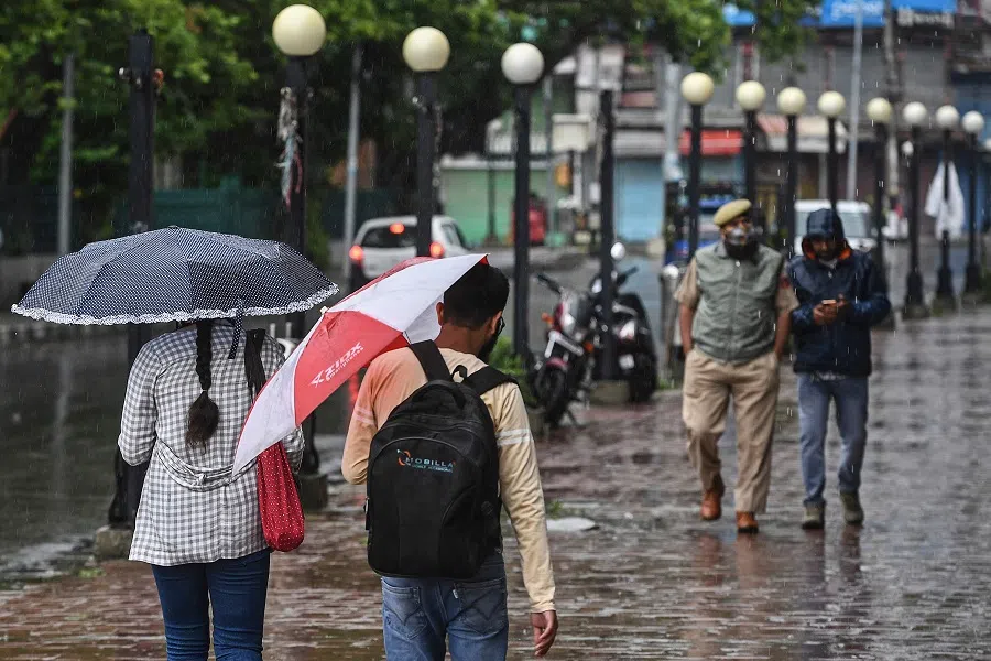 People walk on a sidewalk in Srinagar, India on 15 June 2021. (Tauseef Mustafa/AFP)