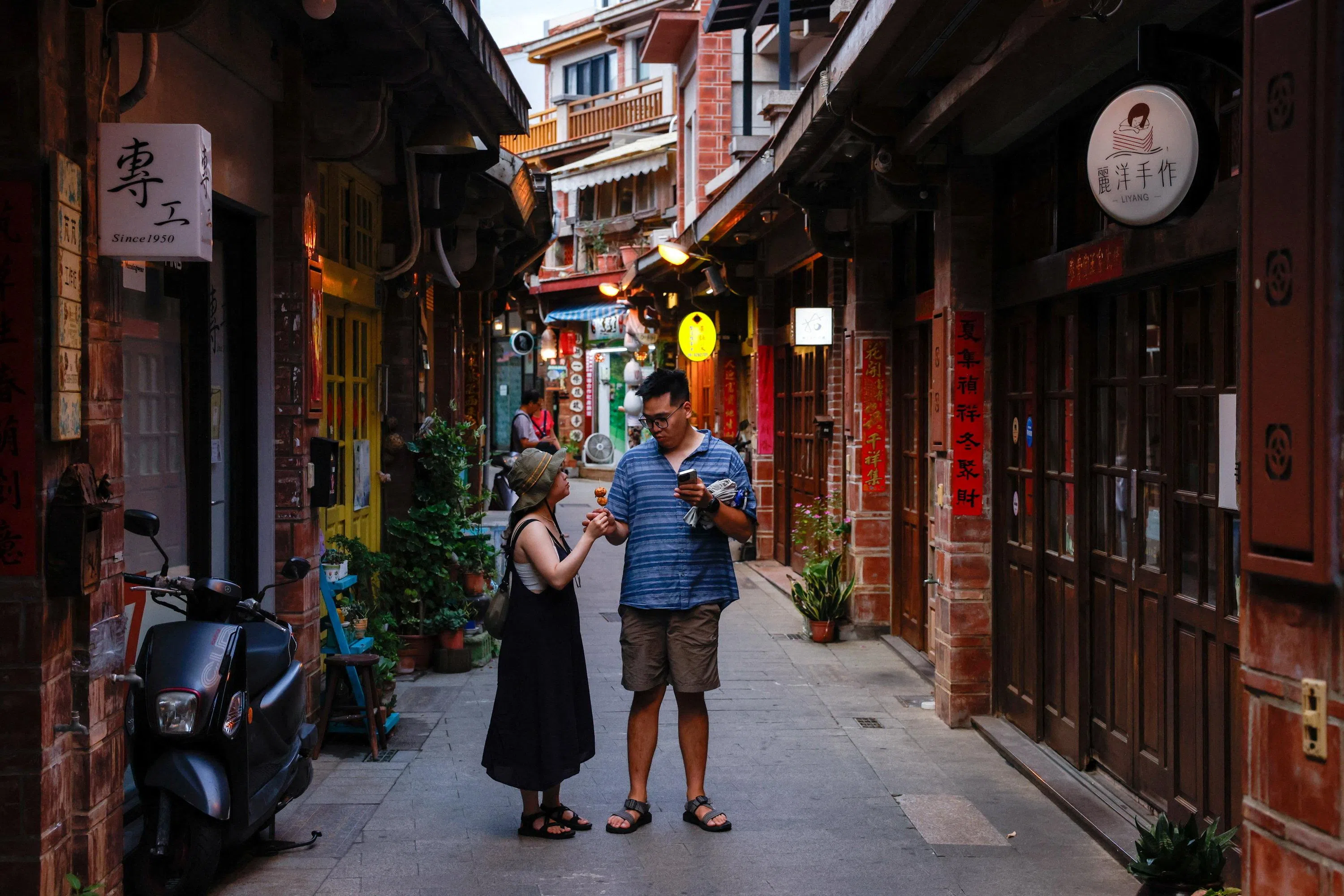 Tourists share food while visiting Zhongyang Old Street, a historic commercial street, in Penghu, Taiwan on 7 June 2026.