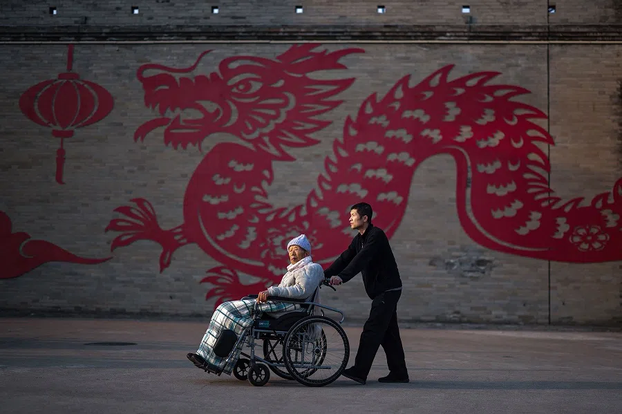 The photo taken on 17 February 2024 shows people passing a dragon decoration to celebrate the Lunar New Year in Luoyang, in central China's Henan province. (AFP)