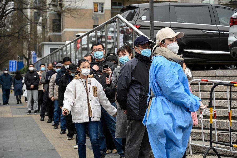 People line up to be tested for Covid-19 at a makeshift testing site along a street in Beijing, China, on 25 March 2022. (Jade Gao/AFP)
