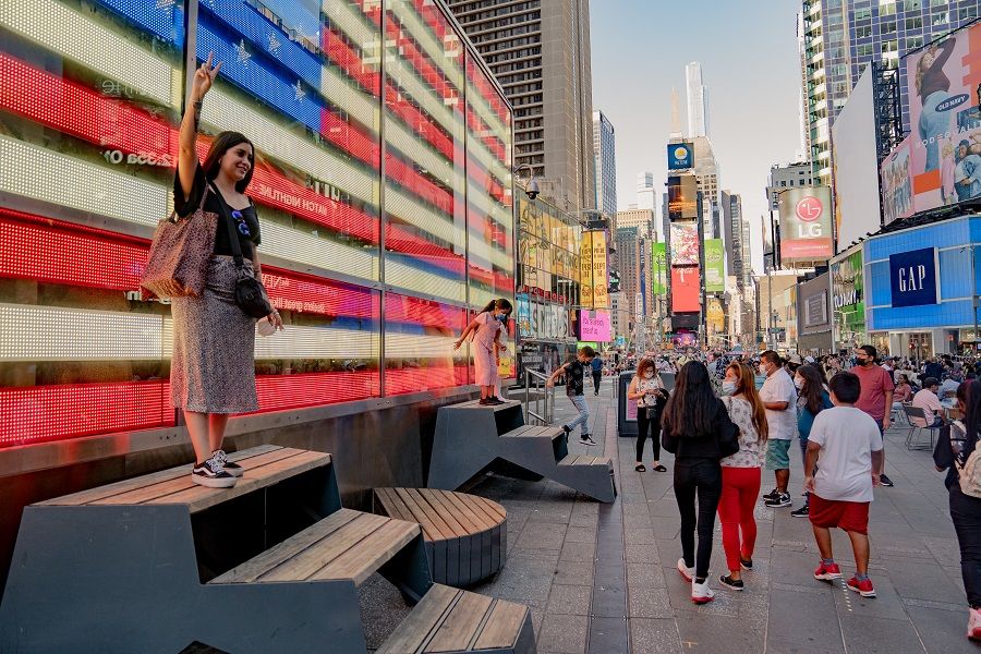 A visitor takes a photograph in front of an electronic American flag in the Times Square neighborhood of New York, US, on 4 September 2021. (Amir Hamja/Bloomberg)