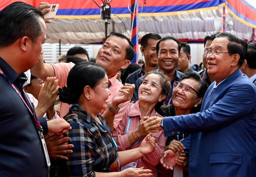 Cambodia's Prime Minister Hun Sen (right) takes selfies with supporters during the inauguration ceremony of the Bakheng-1 water treatment plant in Phnom Penh on 19 June 2023. (Tang Chhin Sothy/AFP)