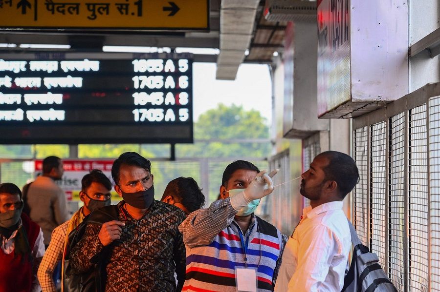 A health worker collects a swab sample for Covid-19 screening from a passenger arriving at Prayagraj Junction, Allahabad, India, on 23 December 2022. (Sanjay Kanojia/AFP)