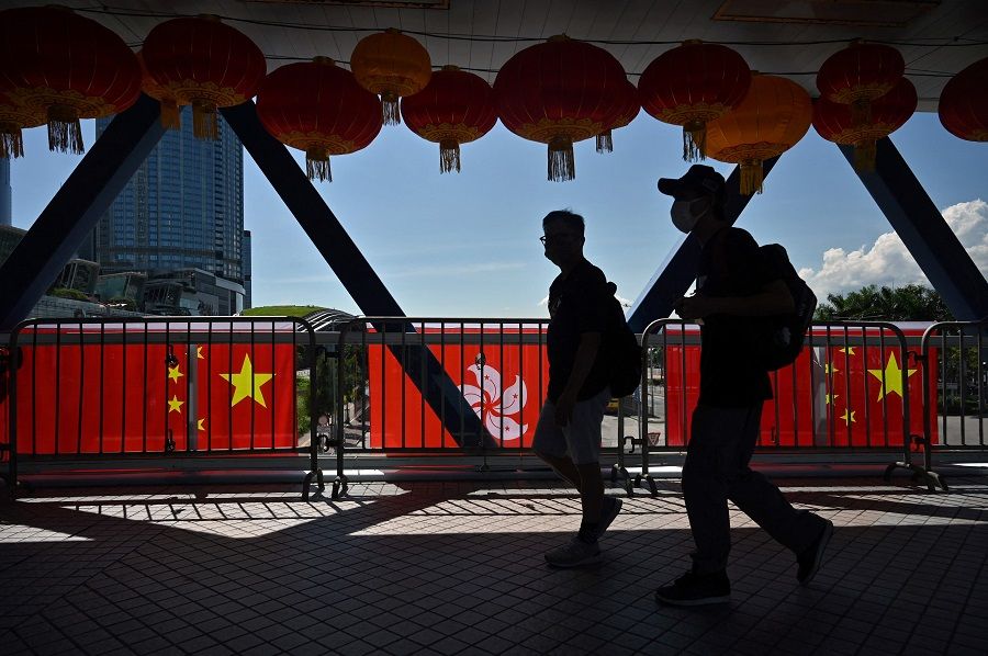 Pedestrians walk past Hong Kong and China flags, hung to mark the 25th anniversary of the Handover of Hong Kong from Britain to China which falls on 1 July, in the Central district of Hong Kong on 28 June 2022. (Peter Parks/AFP)