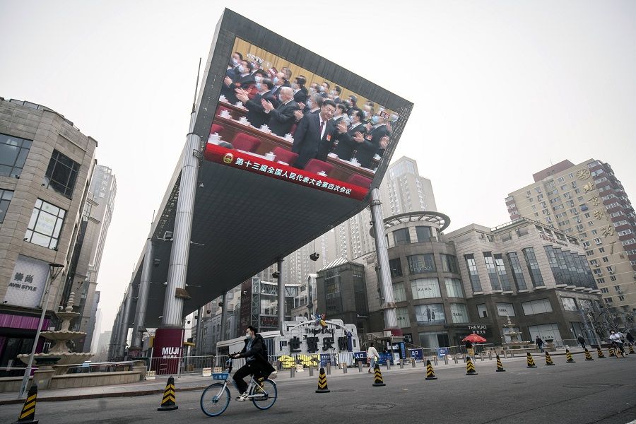 A cyclist rides past a screen showing a live news broadcast of Chinese President Xi Jinping arriving at the National People's Congress in Beijing, China, on 5 March 2021. (Qilai Shen/Bloomberg)