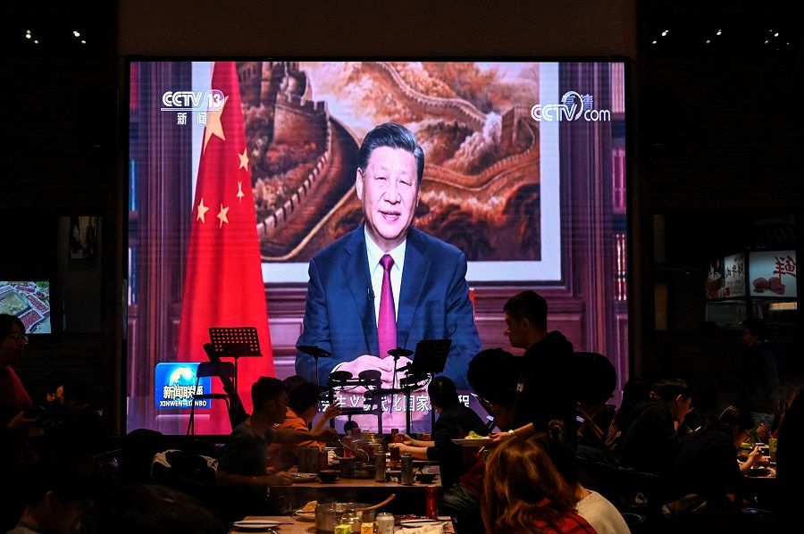 People have their dinner at a restaurant as a screen broadcasts Chinese President Xi Jinping delivering his New Year speech in Beijing, China, on 31 December 2021. (Jade Gao/AFP)