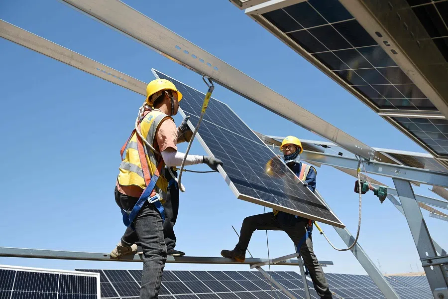 Workers install solar panels at the Ningguoyun Lingwu 1 million kilowatt photovoltaic project in the desert at Lingwu, Ningxia region, China, on 14 April 2025. (AFP)