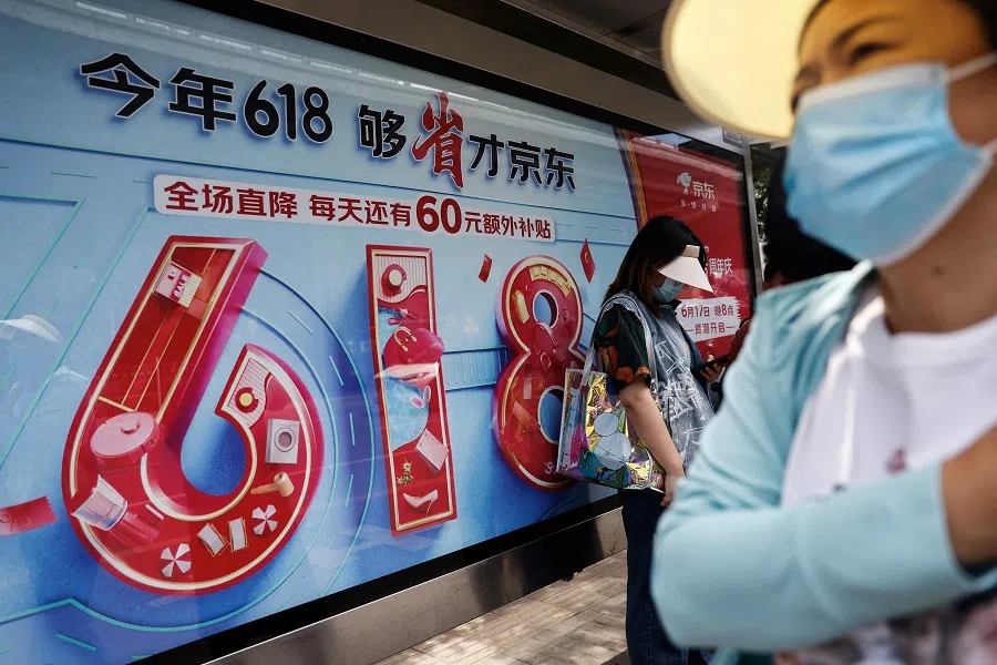 People near a billboard of JD.com's advertisement for the 618 shopping festival, in Beijing, China, on 12 June 2023. (Tingshu Wang/Reuters)