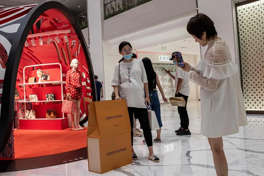 A woman poses for a photo with her Louis Vuitton shopping bags in a mall in Beijing on 14 August 2020. (Nicolas Asfouri/AFP)