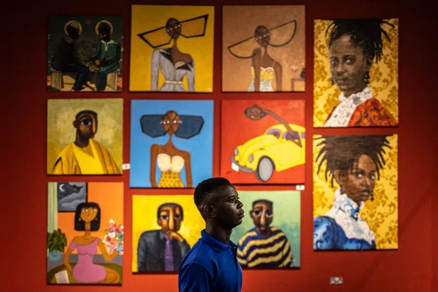 An attendee walks next to artworks from Nigerian artists during a private viewing of the +234 Art fair at Ecobank Pan-African Center in Lagos, on 26 March 2025. (Olympia de Maismont/AFP)