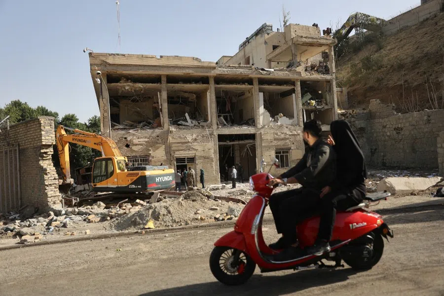 People ride on a motorcycle as a view shows the aftermath of an Israeli strike on Evin Prison that took place on 23 June, after the ceasefire between Israel and Iran, in Tehran, Iran, on 29 June 2025.  (Majid Asgaripour/WANA (West Asia News Agency) via Reuters)