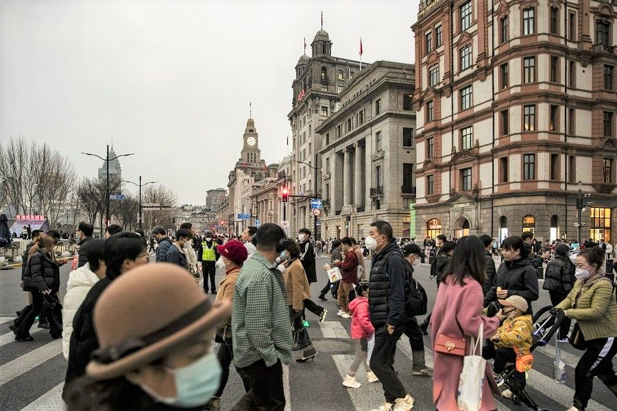 Pedestrians cross a road in Shanghai, China, on 28 February 2023. (Qilai Shen/Bloomberg)