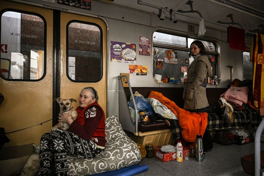 People living in a metro station used as a bomb shelter sit and stand in their sleeping area in a train in Kharkiv, Ukraine, on 26 March 2022. (Aris Messinis/AFP)