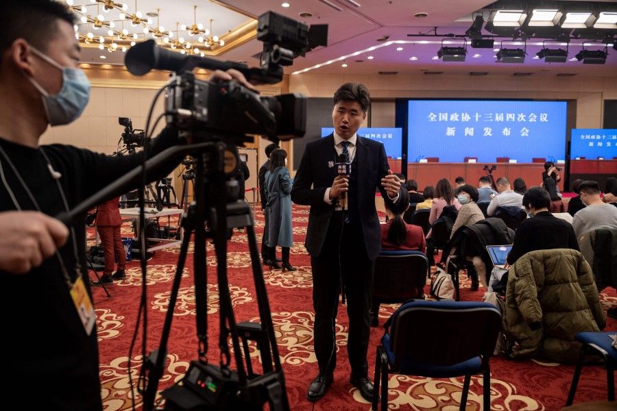 A television journalist works ahead of a press conference at the media centre of the fourth session of the 13th Chinese People's Political Consultative Conference (CPPCC) in Beijing on 3 March 2021. (Nicolas Asfouri/AFP)