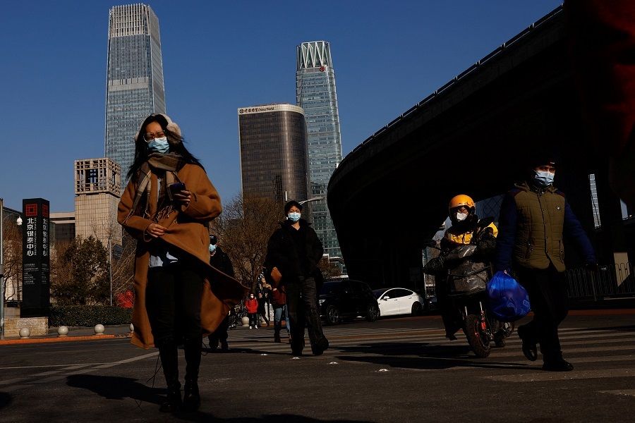 People walk on a street in Beijing's central business district during the morning rush hour in Beijing, China, 30 January 2023. (Tingshu Wang/Reuters)