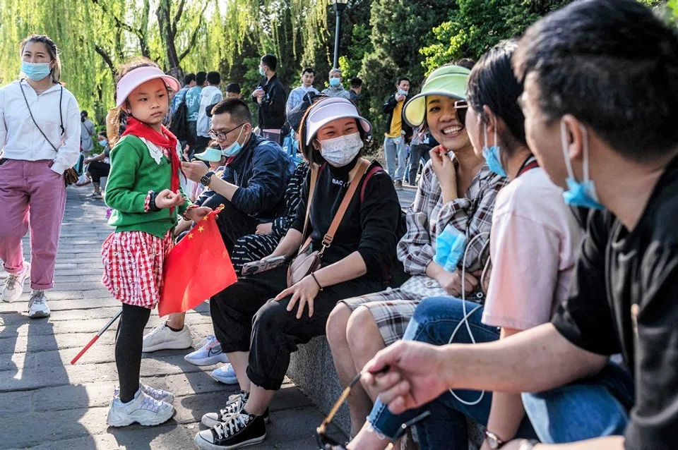 A girl holding a national flag watches as her family chats, outside the Forbidden City during the Labour Day holiday in Beijing, China on 1 May 2021. (Nicolas Asfouri/AFP)