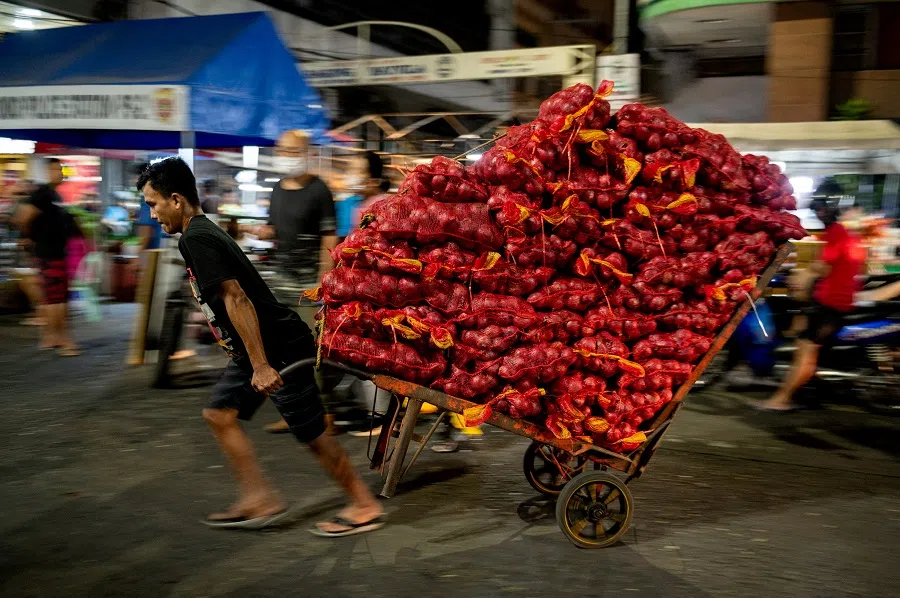 A worker pulls a cart carrying sacks of onions at a public market in Manila, Philippines, on 28 January 2023. (Lisa Marie David/Reuters)