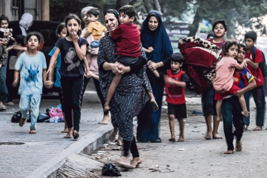 Palestinian women with their children fleeing from their homes following Israeli air strikes rush along a street in Gaza City on 11 October 2023. (Mohammed Abed/AFP)