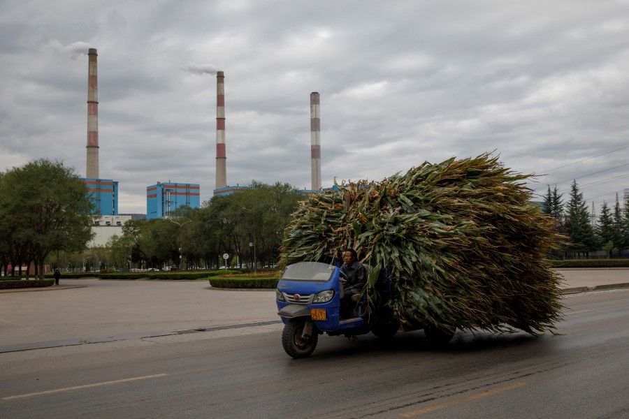 A farmer drives a truck loaded with corn past Huaneng's Pingliang coal-fired power plant in the Kongtong District of Pingliang, Gansu province, China, 19 September 2020. (Thomas Peter/Reuters)