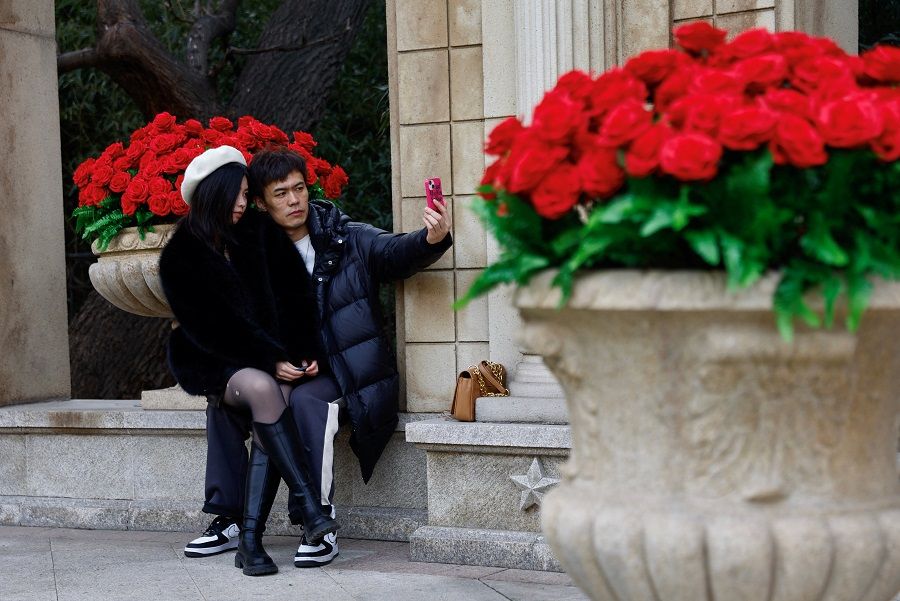 A couple poses for pictures in front of rose installations on Valentine's Day in Beijing, China, 14 February 2023. (Tingshu Wang/Reuters)