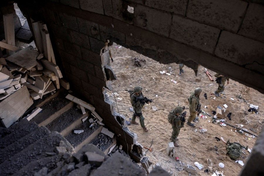 Israeli soldiers walk through rubble, amid the ongoing ground invasion against Hamas in the northern Gaza Strip, on 8 November 2023. (Ronen Zvulun/Reuters)
