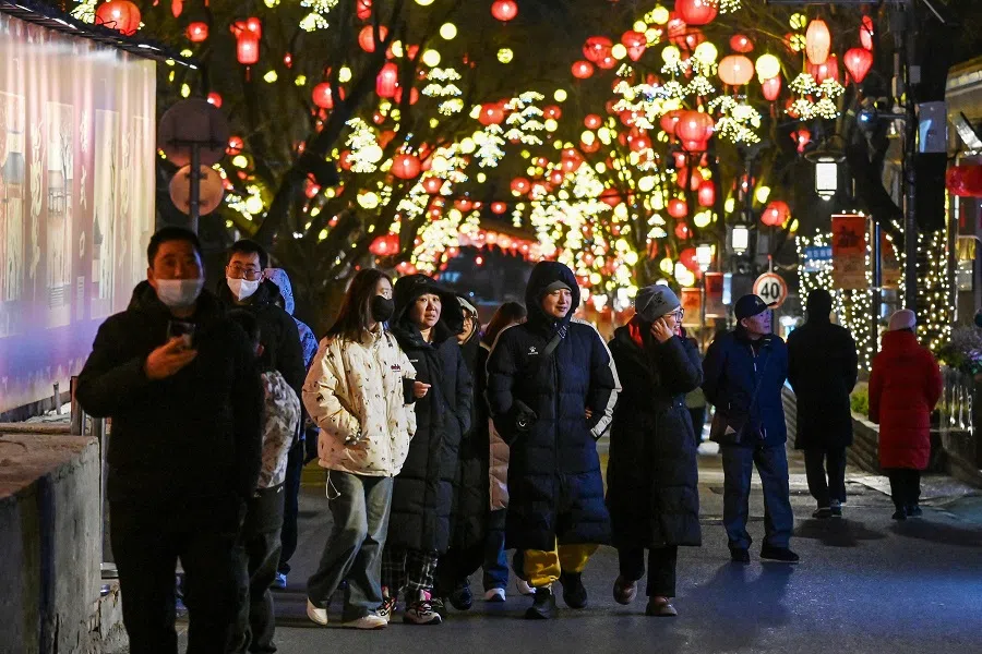 People walk in a street decorated with lanterns in Beijing on 28 January 2025. (Greg Baker/AFP)
