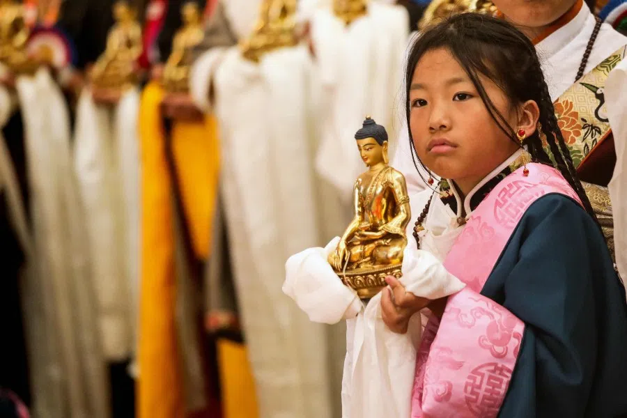 A Buddhist devotee holds a golden Buddha figurine as she waits for the arrival of Tibetan spiritual leader the Dalai Lama, before the start of a Long Life Prayer offering ceremony at the Main Tibetan Temple in McLeod Ganj, near Dharamsala on 30 June 2025. (Sanjay Baid/AFP)