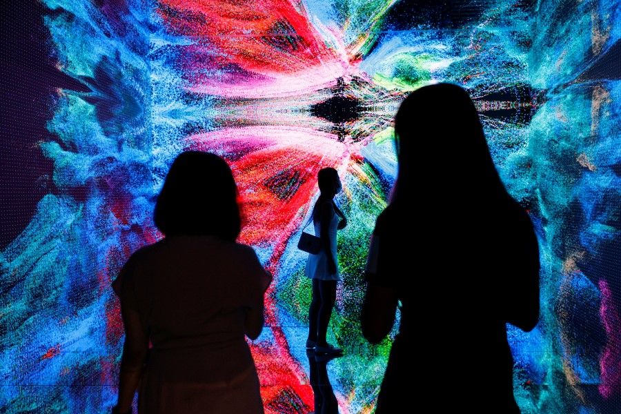 Visitors are pictured in front of an immersive art installation titled "Machine Hallucinations - Space: Metaverse" by media artist Refik Anadol, at the Digital Art Fair, in Hong Kong, China, 30 September 2021. (Tyrone Siu/Reuters)