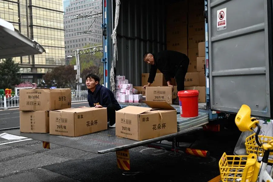 Workers unload boxes from a truck on a street in Beijing, in China, on 9 April 2026. (Pedro Pardo/AFP)