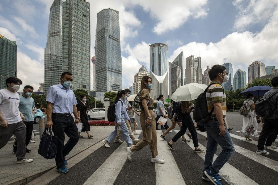 Pedestrians cross a road in Pudong's Lujiazui Financial District in Shanghai, China, on 20 June 2022. (Qilai Shen/Bloomberg)