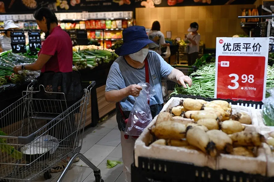 A woman selects vegetables at a supermarket in Beijing on 9 July 2025. (Wang Zhao/AFP)