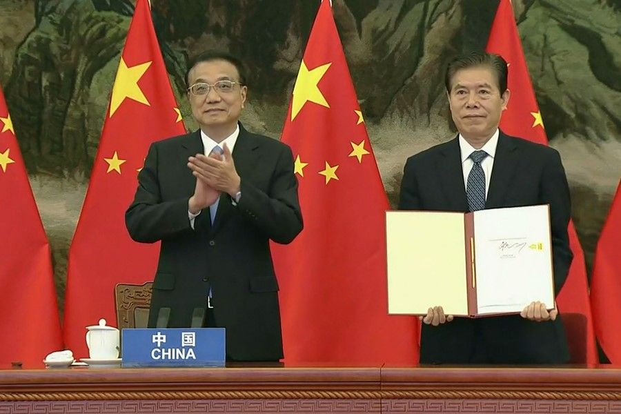 A screen grab taken from Vietnam Host Broadcaster's 15 November 2020 live video shows China's Premier Li Keqiang (L) clapping as Chinese Minister of Commerce Zhong Shan (R) holds up the agreement during the signing ceremony for the Regional Comprehensive Economic Partnership (RCEP) trade pact at the ASEAN summit that is being held online in Hanoi. (Handout/Vietnam host broadcaster/AFP)
