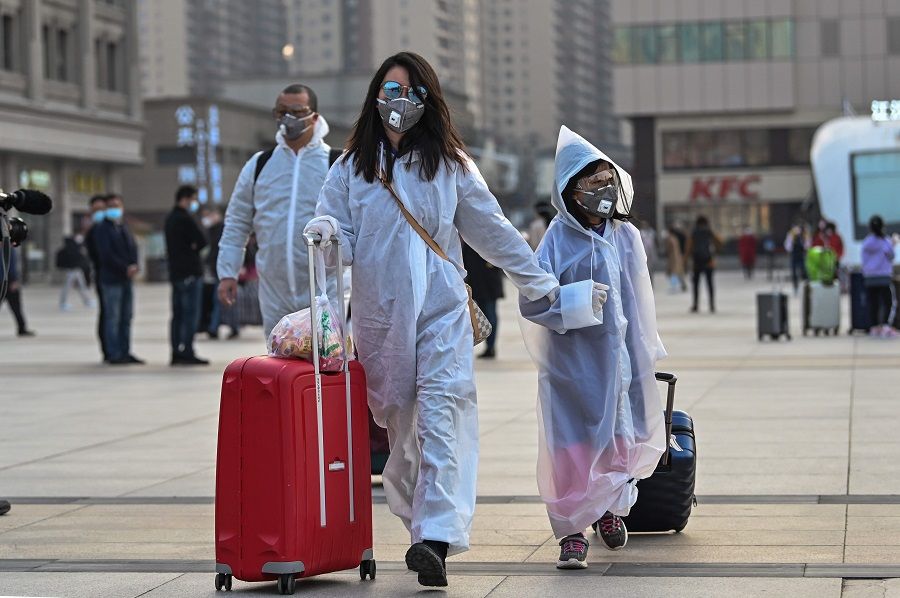 People wearing protective clothing and masks arrive at Hankou Railway Station in Wuhan, to board one of the first trains leaving the city in China's Hubei province early on 8 April 2020, after a ban on outward travel was lifted. (Hector Retamal/AFP)