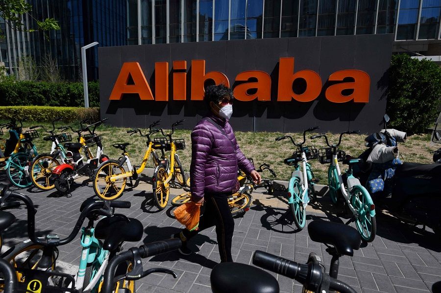 A woman walks past an Alibaba sign outside the company's office in Beijing, China, on 13 April 2021. (Greg Baker/AFP)
