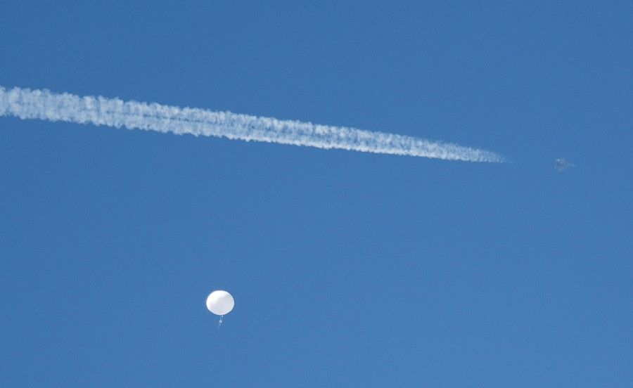 A jet flies by a suspected Chinese spy balloon as it floats off the coast in Surfside Beach, South Carolina, US, 4 February 2023. (Randall Hill/Reuters)