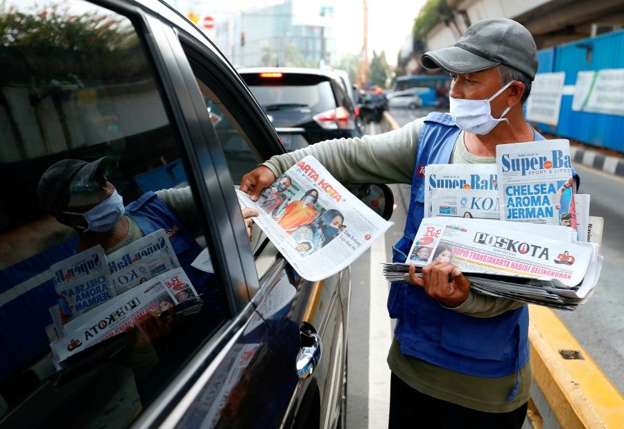 A vendor sells newspapers along a highway in Jakarta, Indonesia, 10 June 2020. (Ajeng Dinar Ulfiana/REUTERS)