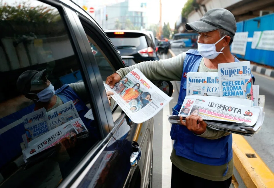 A vendor sells newspapers along a highway in Jakarta, Indonesia, 10 June 2020. (Ajeng Dinar Ulfiana/REUTERS)