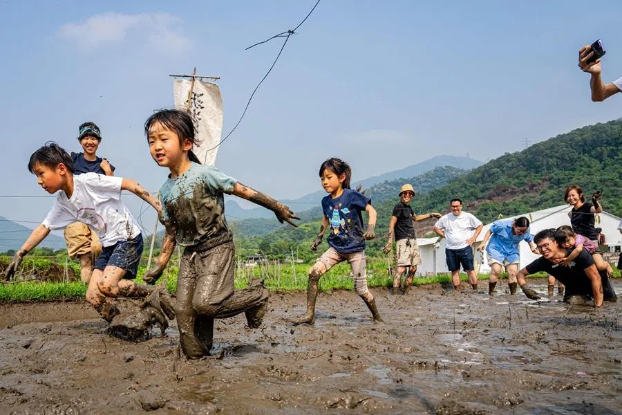 Children take part in an activity in a muddy field in Hong Kong on 18 April 2026. (Leung Man Hei/AFP)