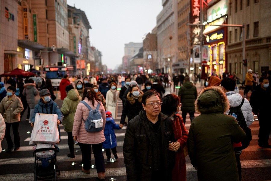 People walk along Wangfujing shopping street in Beijing on 14 February 2021. (Noel Celis/AFP)