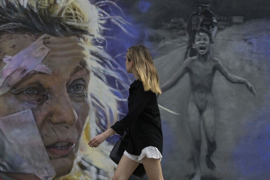 A woman walks pass the mural "No to war" by muralist Maximiliano Bagnasco in Buenos Aires on 5 March 2022. The mural is inspired by two war photographs from Ukraine and Vietnam. (Juan Mabromata/AFP)