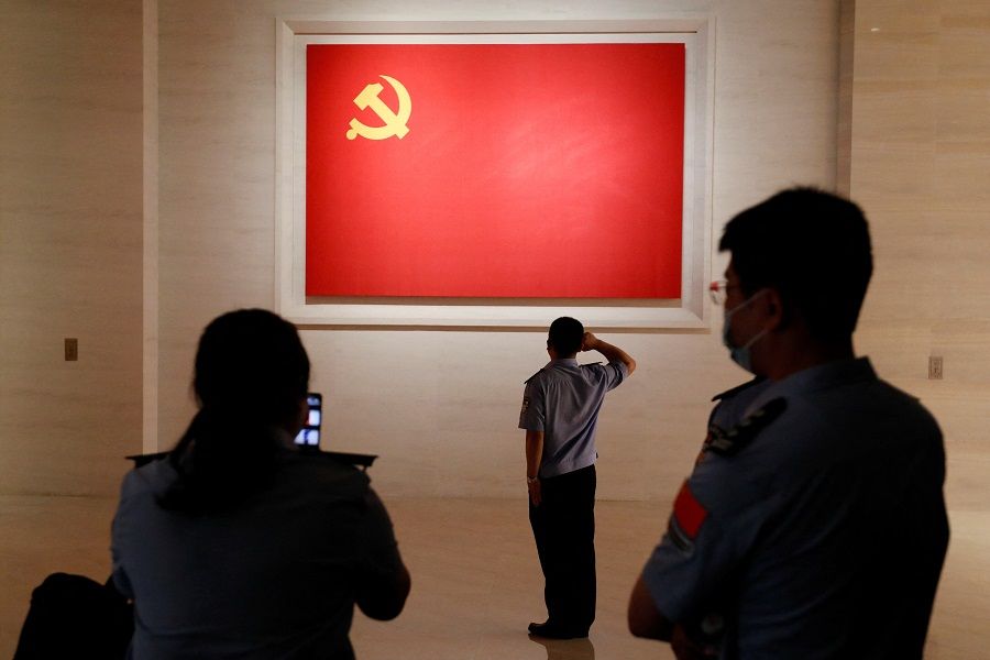 A police officer poses for a picture in front of a Chinese Communist Party flag at the Museum of the Communist Party of China in Beijing, China, 3 September 2022. (Florence Lo/Reuters)