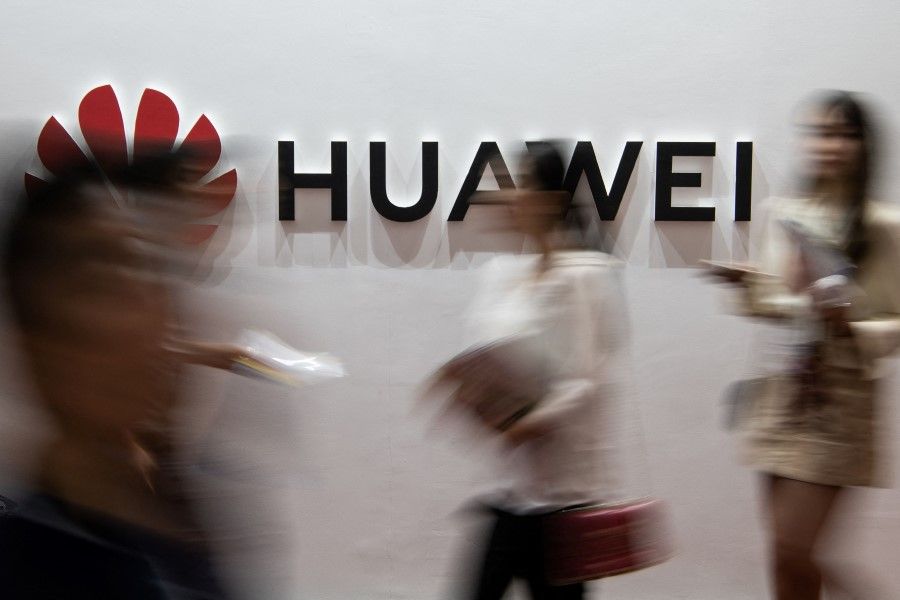 People walk past a Huawei logo during the Consumer Electronics Expo in Beijing in this file photo taken on 2 August 2019. (Fred Dufour/AFP)