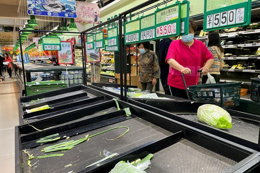 Customers wearing face masks shop next to near-empty shelves at a supermarket following the Covid-19 outbreak in Chaoyang District of Beijing, China, 24 April 2022. (Carlos Garcia Rawlins/Reuters)